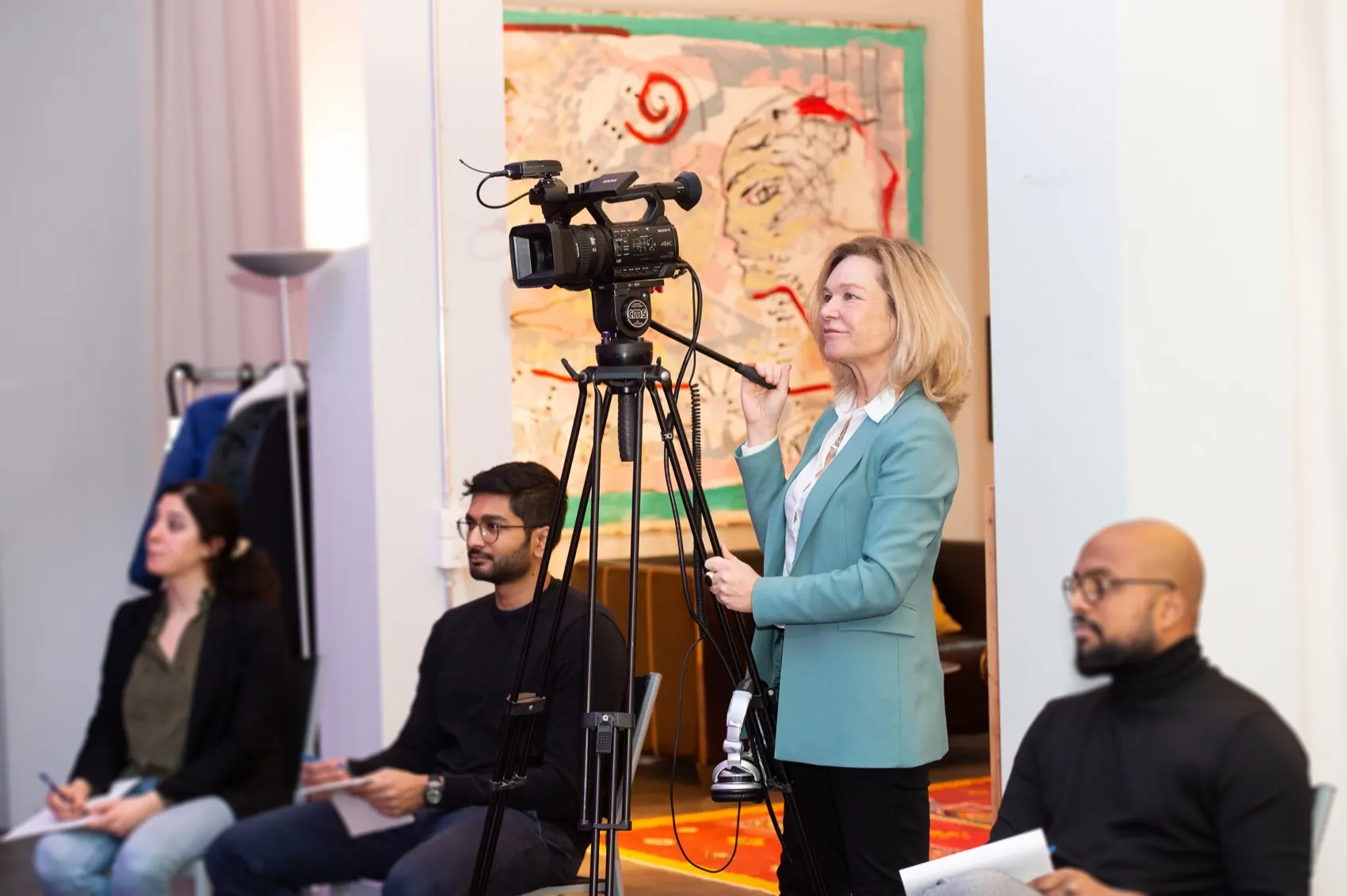 Des participants sont assis dans le Speak-Studio devant une caméra vidéo ; une formatrice se tient devant un paperboard.